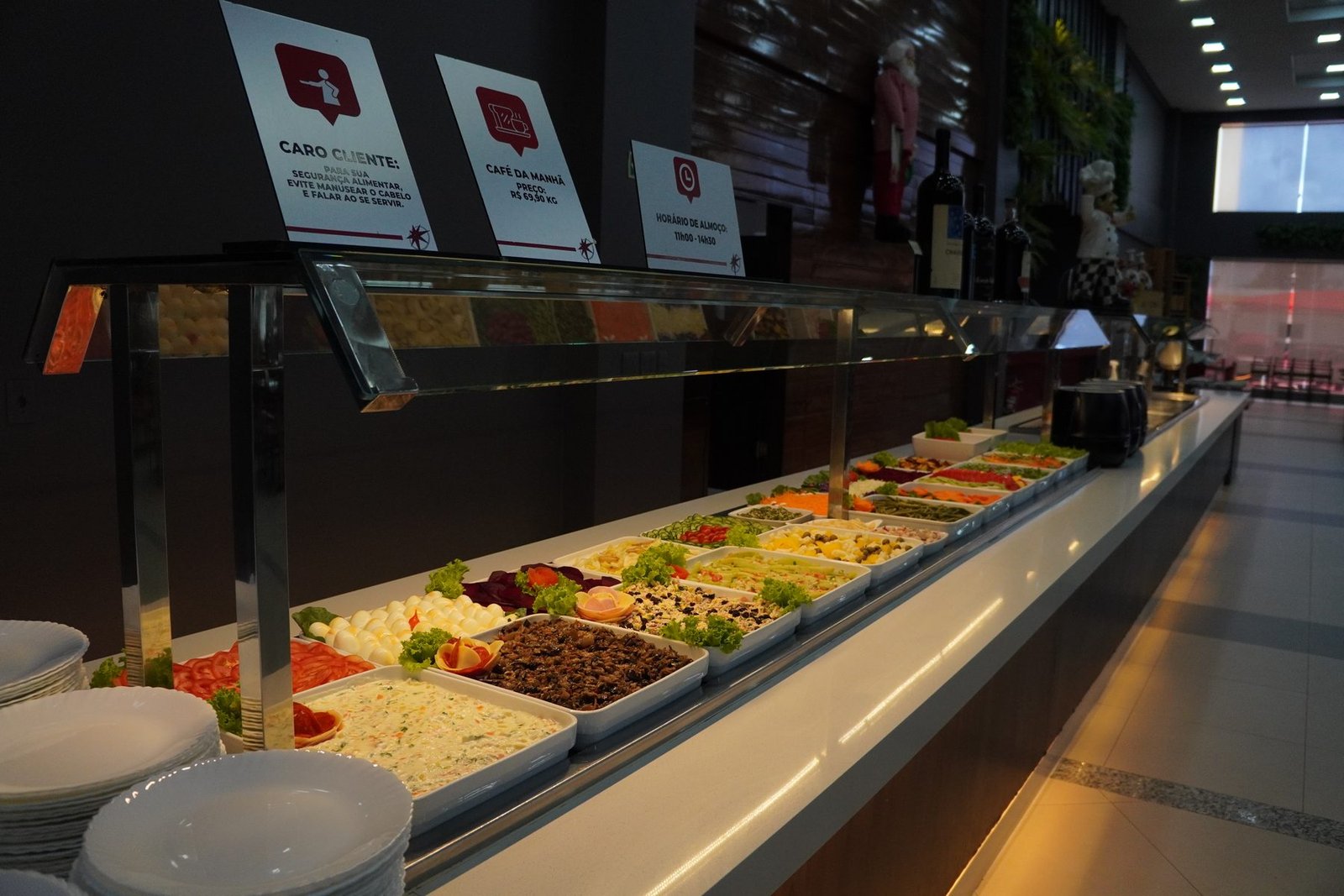 Ilha de saladas do buffet, com placas de horário e preço